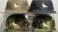three camouflage hats are on display in a display case